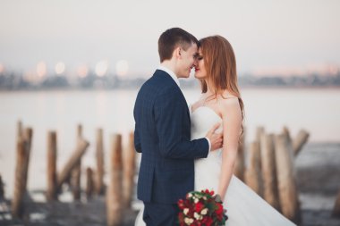 Çift düğün, damat, gelin buketi günbatımı üzerinde denize yakın poz ile