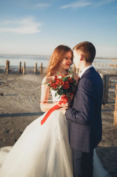 Elegáns elegáns boldog esküvő pár, menyasszony, gyönyörű vőlegény a háttérben a tenger és az ég — Stock Fotó