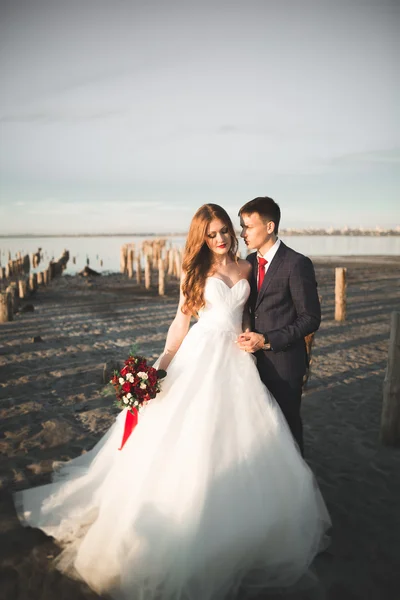 Çift düğün, damat, gelin buketi günbatımı üzerinde denize yakın poz ile — Stok fotoğraf