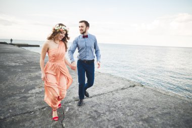 Güzel sevgi dolu çift, gurur iskelede yürüyüş uzun elbise ile