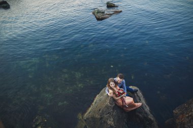 Mavi Denizi çevresinde büyük bir taş üzerinde oturan Düğün çifti