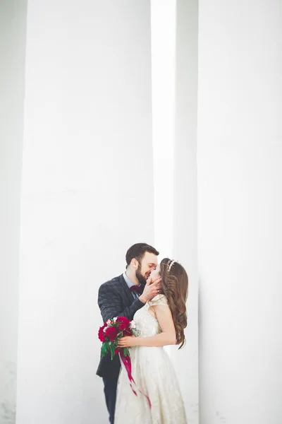 Beautiful couple, bride and groom posing near big white column — Stock Photo, Image