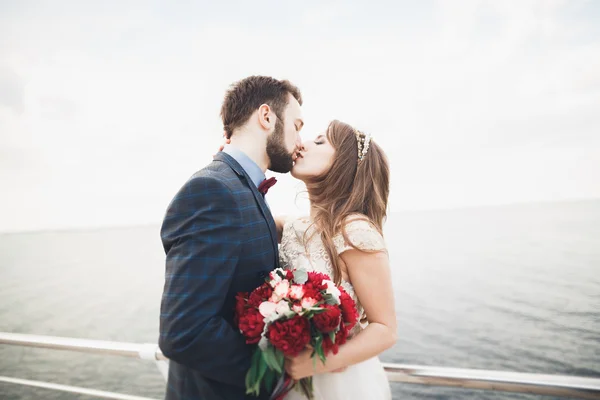 Casada pareja de boda de pie en un muelle sobre el mar — Foto de Stock