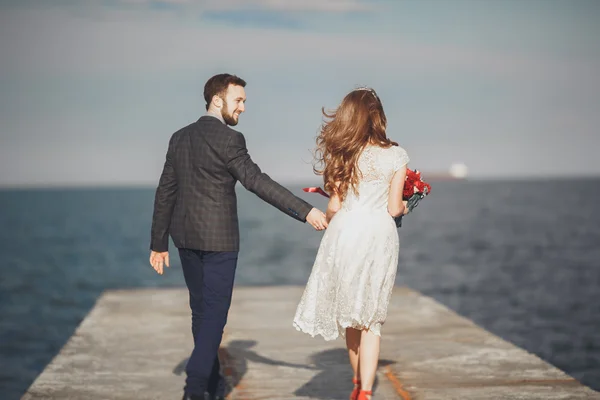 Casamento casal em pé em um cais sobre o mar — Fotografia de Stock