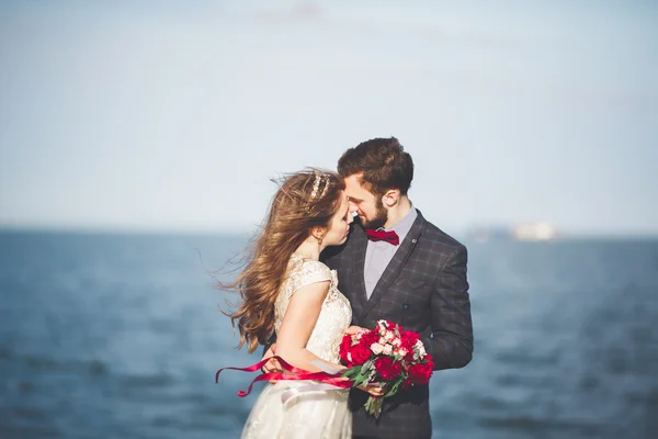 Casada pareja de boda de pie en un muelle sobre el mar — Foto de Stock