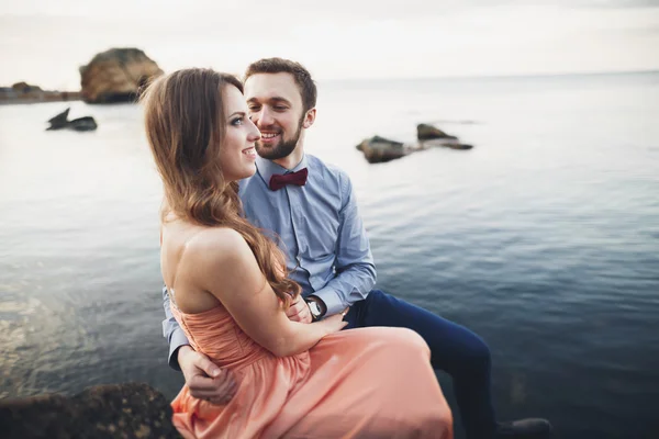 파란색 바다 근처 바위 위에서 키스하고 껴안고 있는 부부 — 스톡 사진