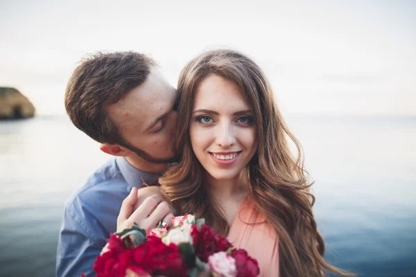 Matrimonio coppia baci e abbracci su rocce vicino al mare blu — Foto Stock