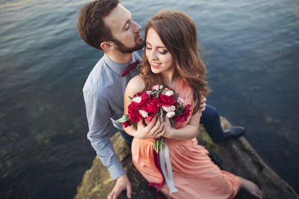 Matrimonio coppia baci e abbracci su rocce vicino al mare blu — Foto Stock