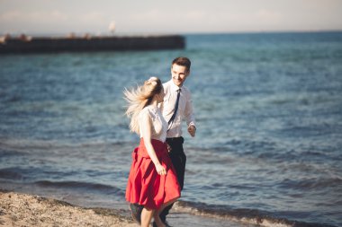 Genç mutlu çift holding birbirlerini etrafında gülümseyen Sahilde yürüyüş. Aşk hikayesi