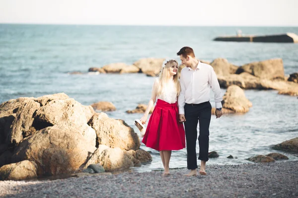 Romántica pareja amorosa posando sobre piedras cerca del mar, cielo azul — Foto de Stock