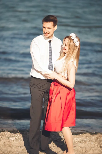 Mladý šťastný pár na pláži s úsměvem hospodářství kolem sebe. Příběh lásky — Stock fotografie