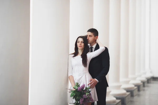 Gyönyörű pár, a menyasszony és a vőlegény jelentő közelében nagy fehér oszlop — Stock Fotó