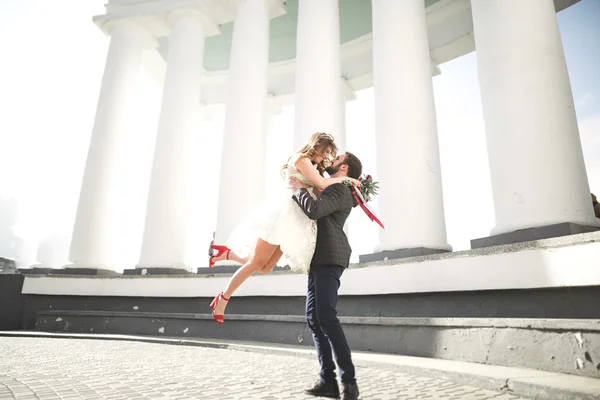 Hermosa pareja, novia y novio posando cerca de gran columna blanca — Foto de Stock