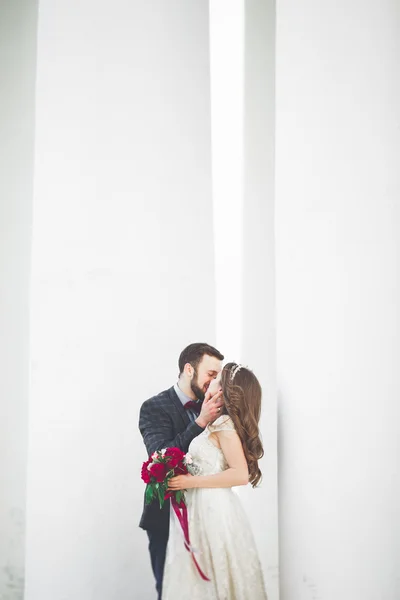 Beautiful couple, bride and groom posing near big white column — Stock Photo, Image