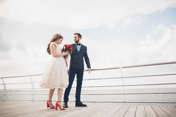 Casada pareja de boda de pie en un muelle sobre el mar — Foto de Stock