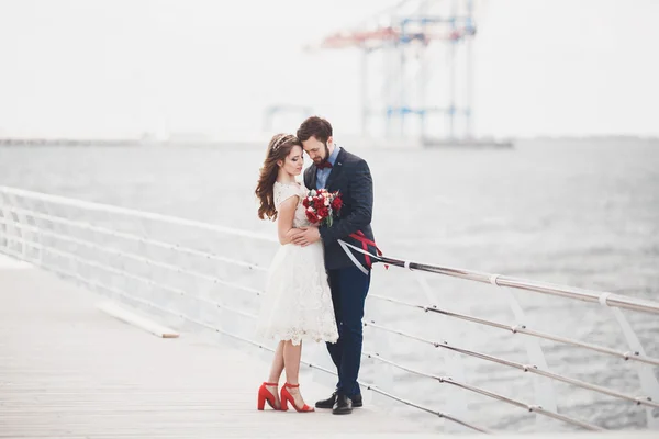 Pareja de recién casados caminando en la playa al atardecer . — Foto de Stock