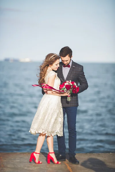 Casamento casal em pé em um cais sobre o mar — Fotografia de Stock