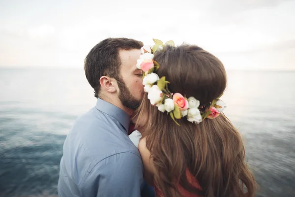 Boda pareja besándose y abrazándose en rocas cerca de mar azul — Foto de Stock