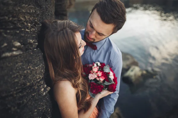 Casamento casal sentado em pedra grande em torno do mar azul — Fotografia de Stock