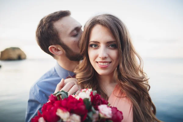 Bröllop par kysser och kramas på stenar nära blå havet — Stockfoto