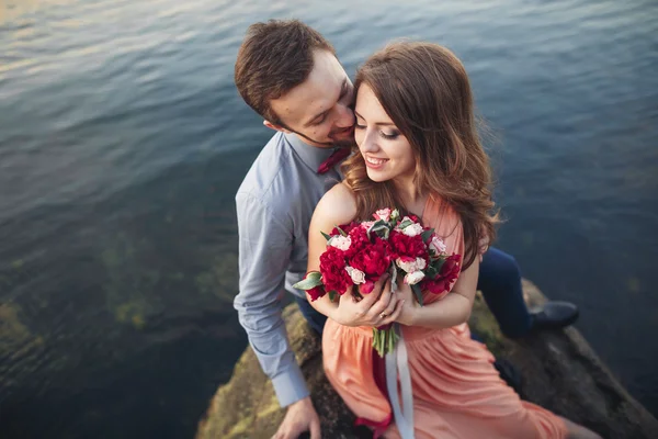 Casamento casal beijando e abraçando em rochas perto do mar azul — Fotografia de Stock