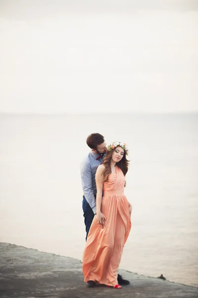 Casamento casal em pé em um cais sobre o mar — Fotografia de Stock