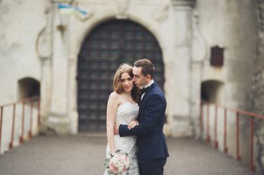 Güzel, romantik bir düğün. Yeni evliler. Eski kalenin yakınlarında sarılıyorlar.