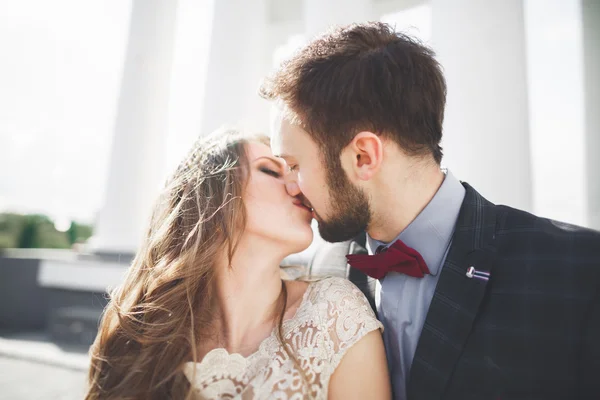 Beautiful couple, bride and groom posing near big white column — Stock Photo, Image