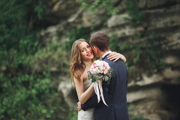 Alegre casada boda pareja posando nea rocas —  Fotos de Stock