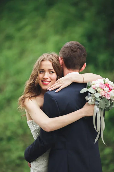 Alegre casada boda pareja posando nea rocas — Foto de Stock