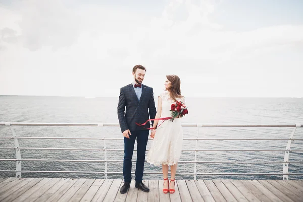 Casamento casal apenas andando na praia ao pôr do sol . — Fotografia de Stock