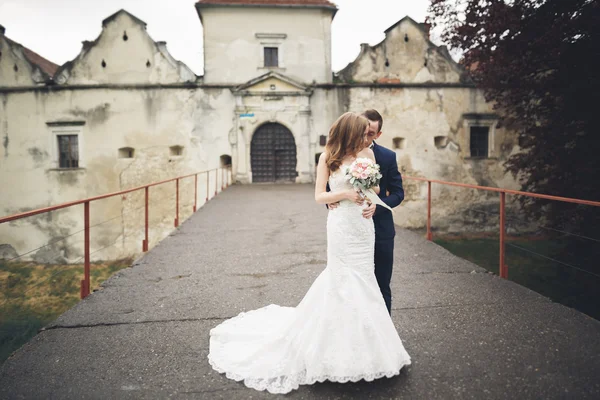 Feliz boda pareja abrazándose y sonriendo el uno al otro en el fondo viejo castillo — Foto de Stock