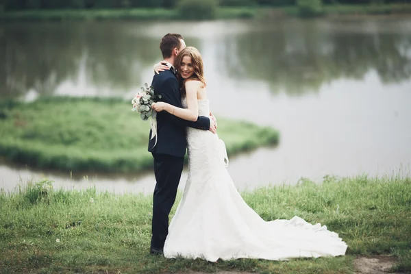 Hermosa pareja de boda besándose y abrazándose cerca del lago con la isla — Foto de Stock