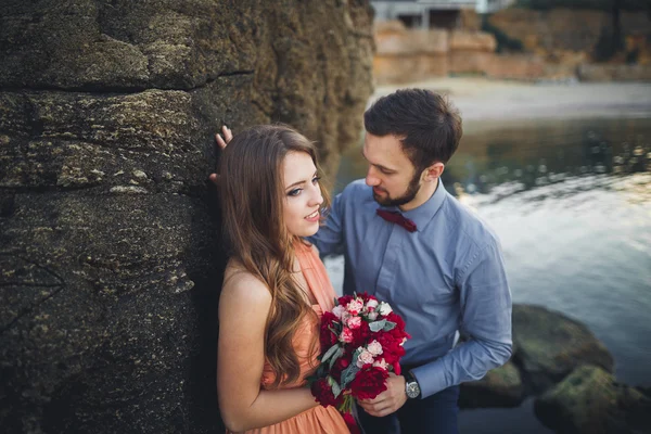 Matrimonio coppia seduta su una grande pietra intorno al mare blu — Foto Stock