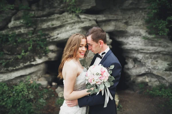 Glückliches Hochzeitspaar umarmt und lächelnd einander auf dem Hintergrund herrliche Pflanzen im Schloss — Stockfoto