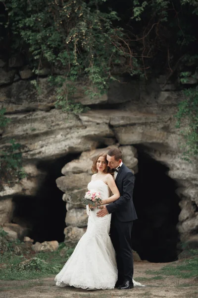 Alegre casada boda pareja posando nea rocas —  Fotos de Stock