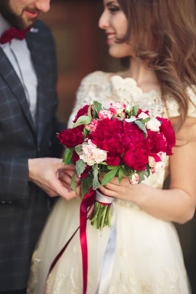 Boda pareja abrazándose, la novia sosteniendo un ramo de flores en su mano, novio abrazando — Foto de Stock