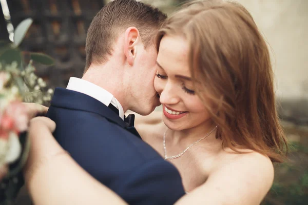 Verheugd huwelijksfeest paar knuffelen en glimlachen elkaar op achtergrond oud kasteel — Stockfoto