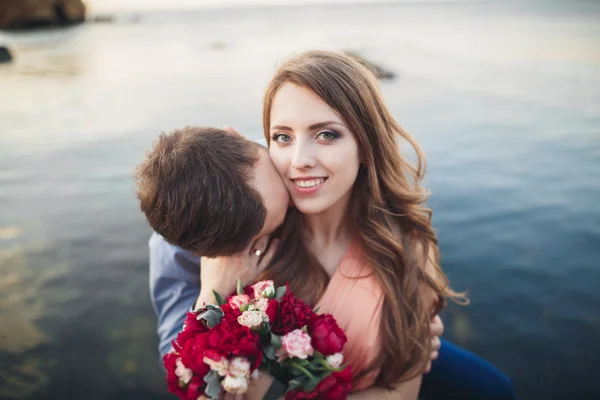 Matrimonio coppia seduta su una grande pietra intorno al mare blu — Foto Stock