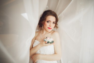 Beyaz elbiseli lüks gelin düğün törenine hazırlanırken poz veriyor.