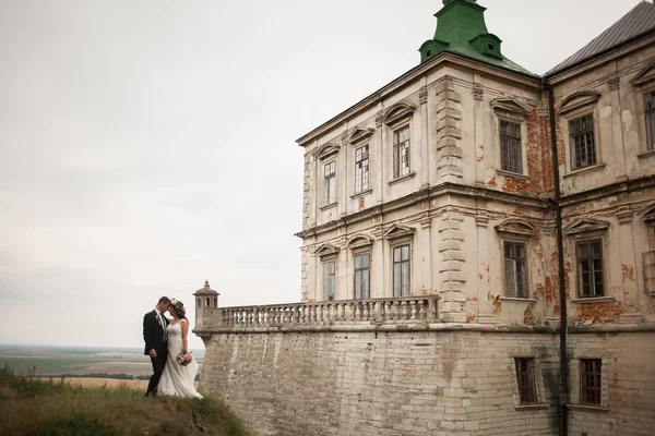 Krásný romantický svatební pár novomanželé objímání v blízkosti starého hradu — Stock fotografie