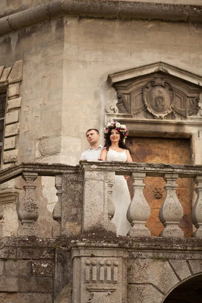Счастливая свадебная пара обнимает и целует на заднем плане старый замок — стоковое фото