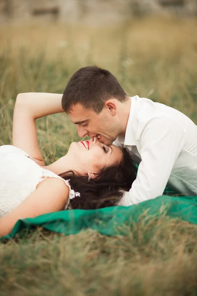 Щаслива весільна пара лежить на зеленій траві в літній час — стокове фото
