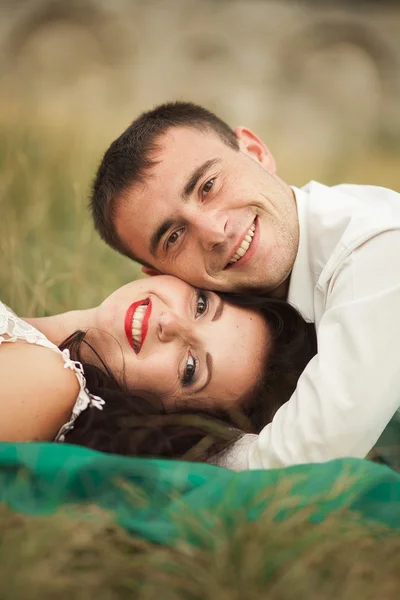 Casal de casamento feliz deitado na grama verde na hora de verão — Fotografia de Stock