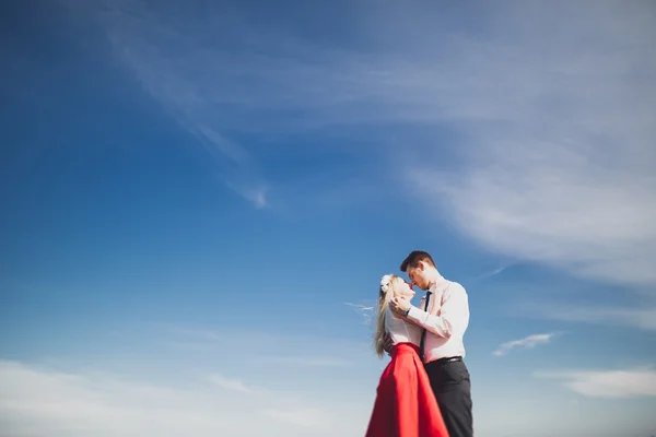 Romántica pareja amorosa posando sobre piedras cerca del mar, cielo azul — Foto de Stock