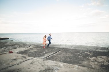 Güzel sevgi dolu çift, gurur iskelede yürüyüş uzun elbise ile