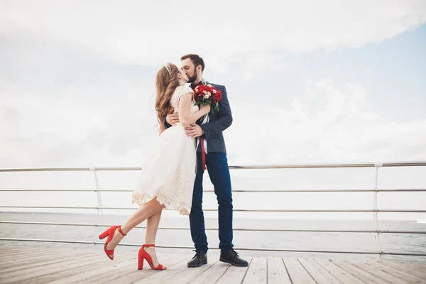 Casamento casal em pé em um cais sobre o mar — Fotografia de Stock