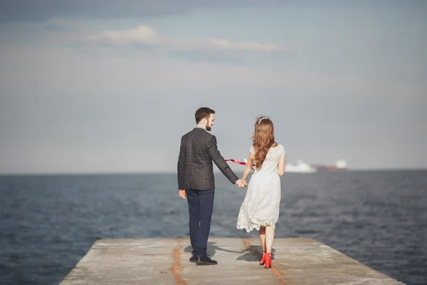 Marié couple marchant sur la plage au coucher du soleil . — Photo