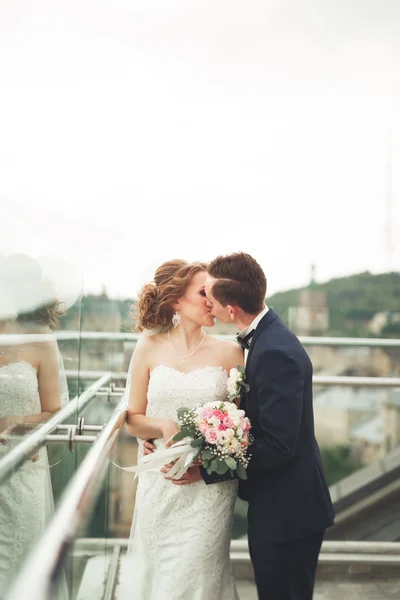 Pasangan yang cantik, pengantin pria dan wanita berpose di balkon dengan latar belakang kota tua — Stok Foto