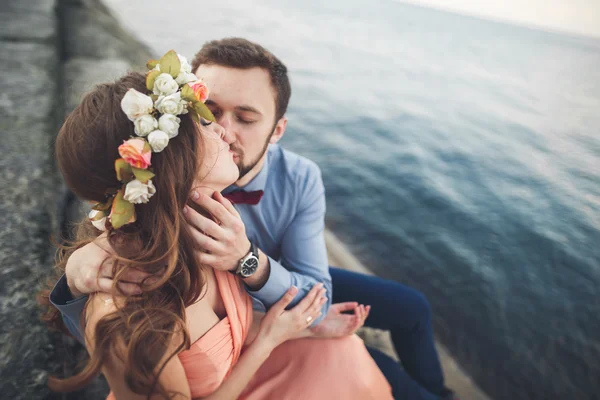 Wedding couple sitting on large stone around blue sea Stock Photo